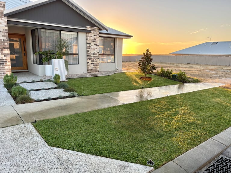 Modern brick house with manicured lawn, concrete pathway, and mountain views at sunset