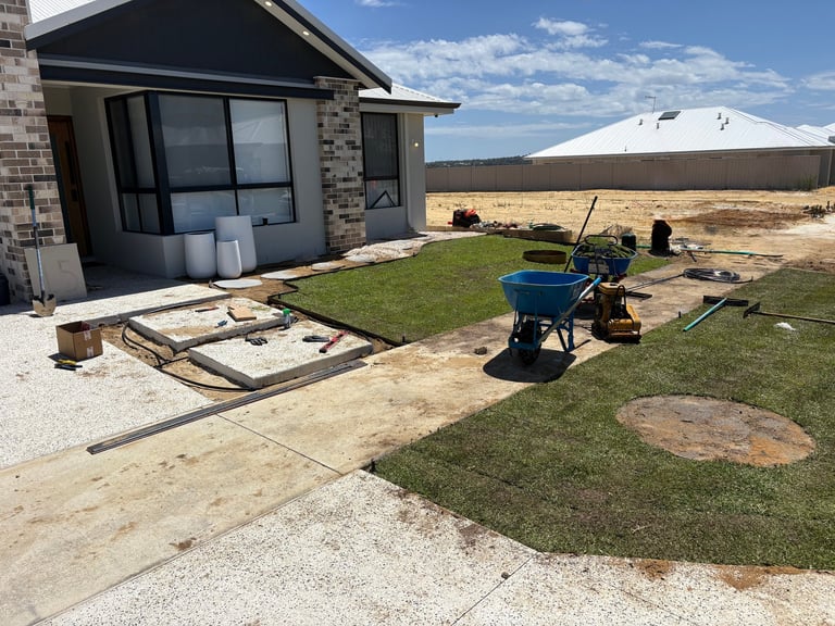 Modern house under construction with blue landscaping equipment on freshly laid sod in rural setting