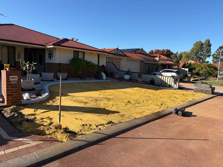 A residential property with single-story brick homes, yellow dirt lot in front, clear blue sky, and driveway