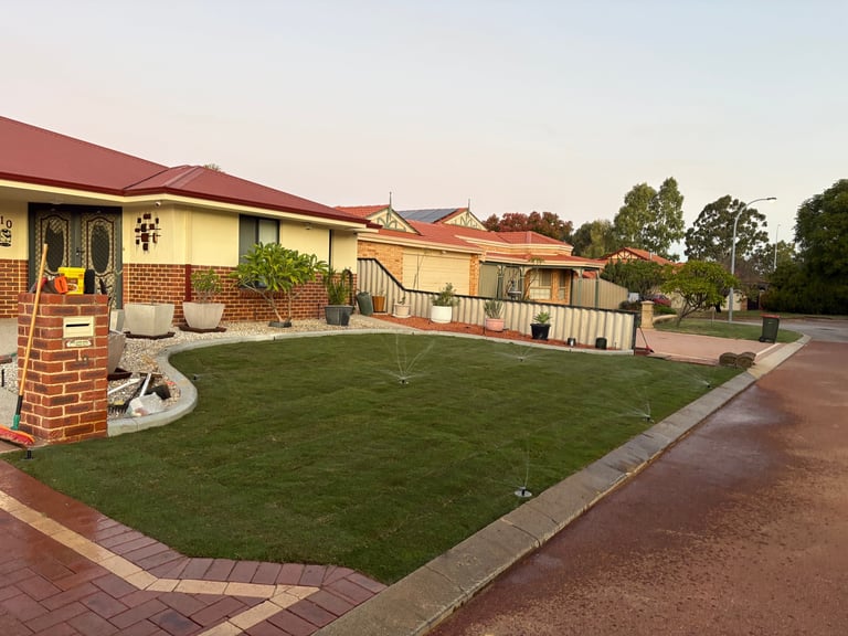 Residential home with brick exterior, red roof, and manicured lawn in rural area at dusk